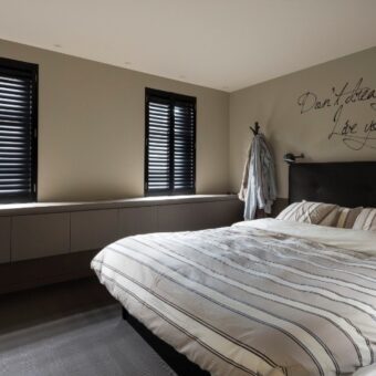 Zwarte shutters bij bed