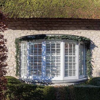 Buitenaanzicht van witte shutters in erker