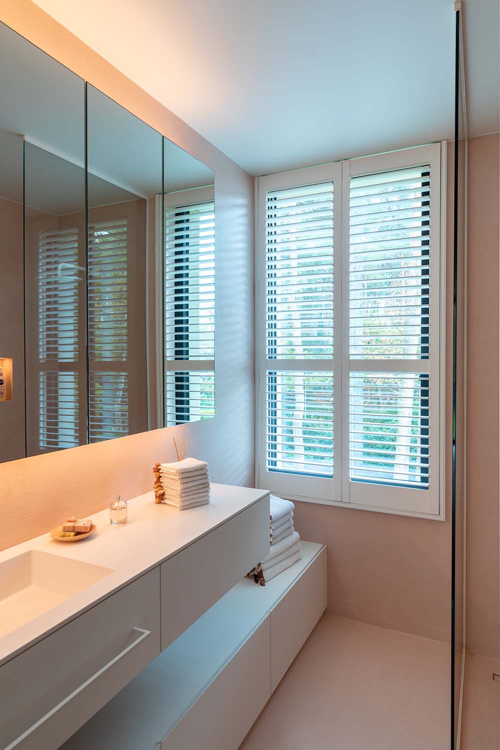 Shutters blancs dans la salle de bain rose