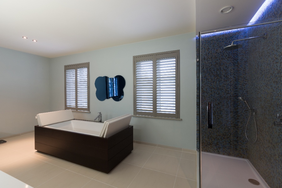 Shutters en matière synthétique dans une grande salle de bains avec baignoire