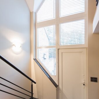 Schuine ramen met witte shutters bij voordeur