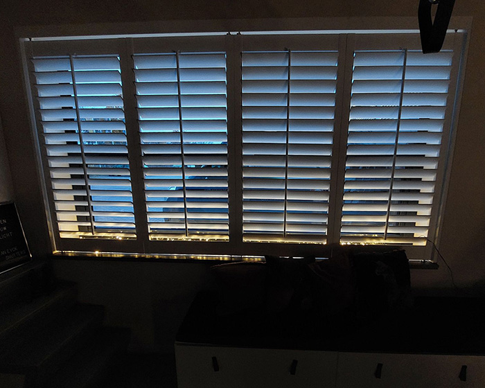 Witte shutters met kerstverlichting in raamkozijn