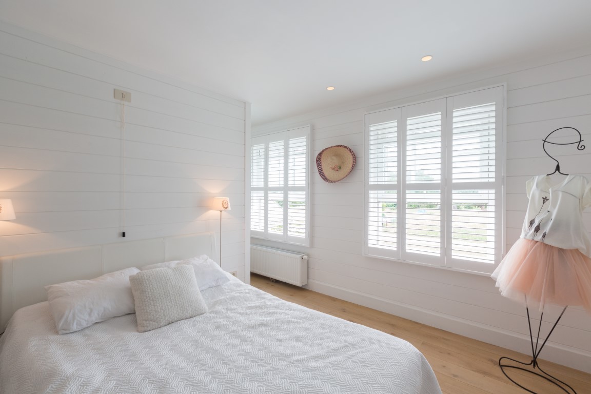 Slaapkamer met witte houten shutters
