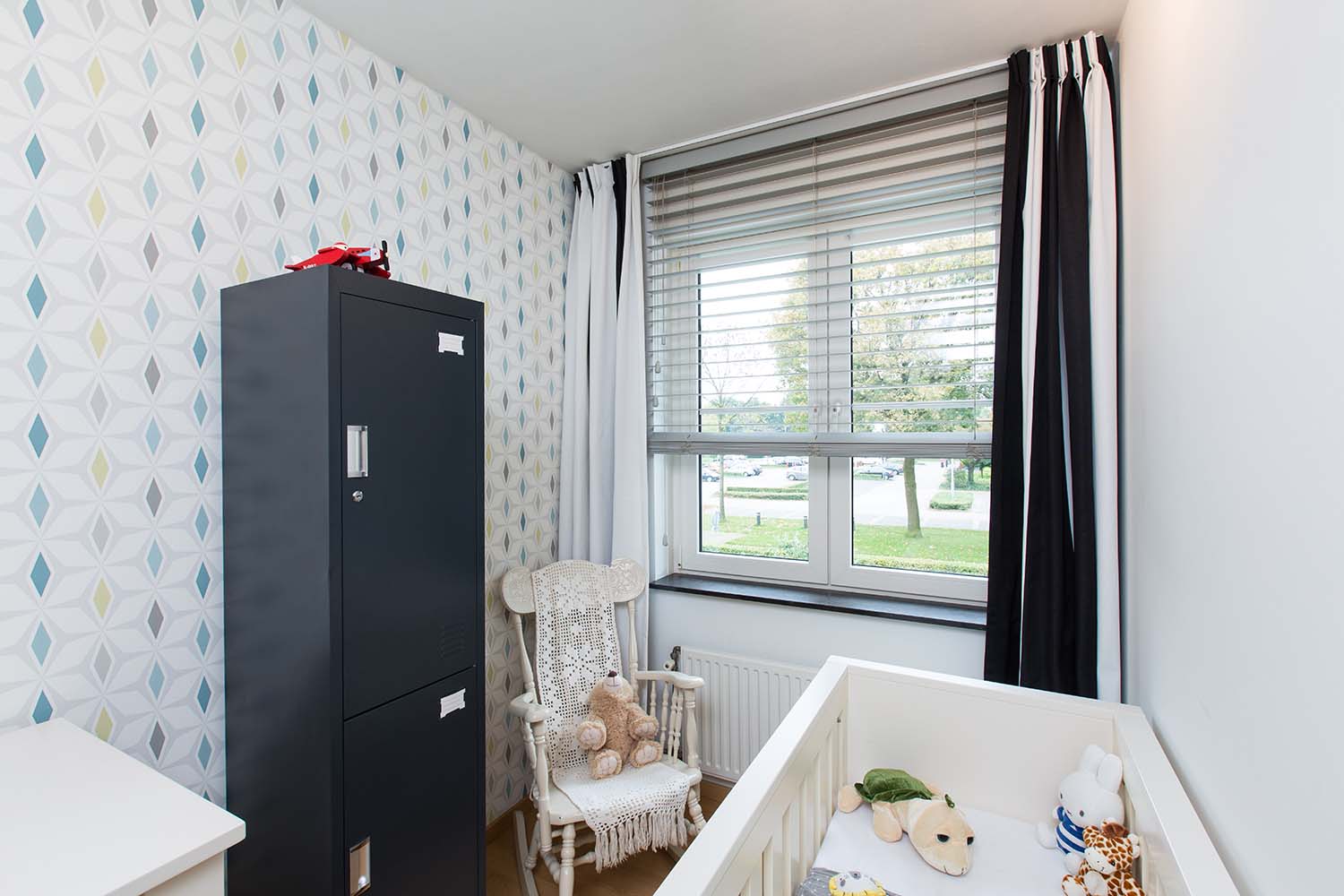Geopende jaloezieën als raamdecoratie van kinderkamer