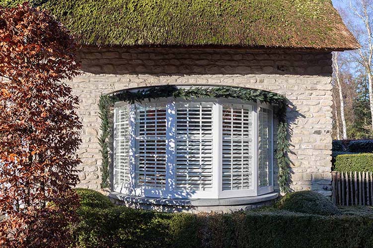 Buitenaanzicht van witte shutters in erker