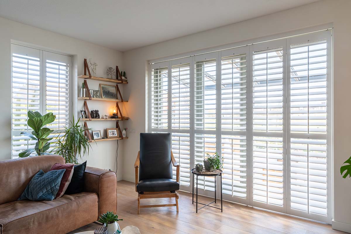 Woonkamer met witte shutters in ramen tot de vloer
