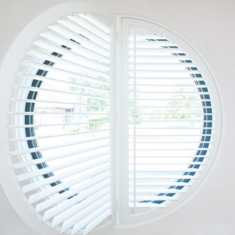 Witte shutters in klein rond raam