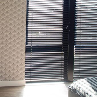 Zwarte jaloezieën in retro slaapkamer
