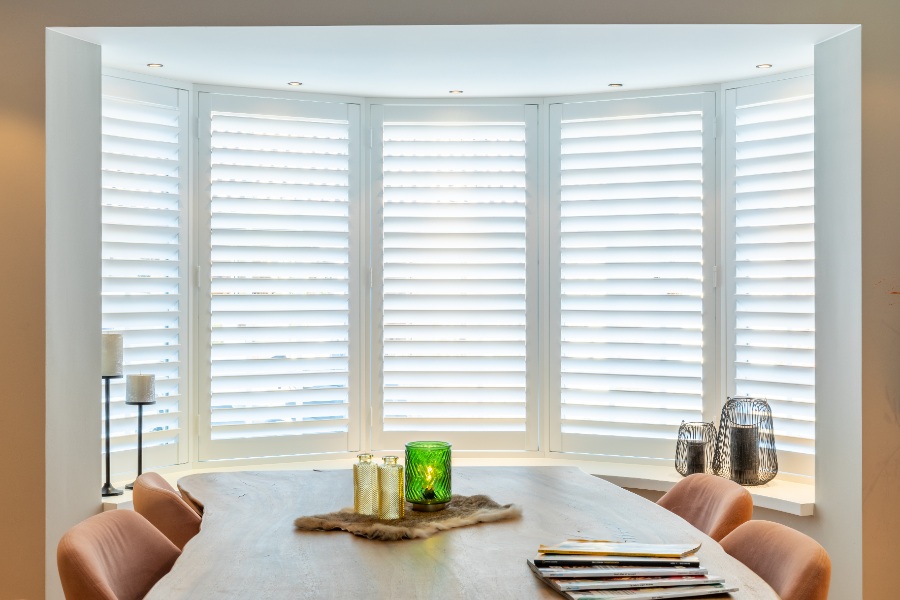Witte shutters in het raam van een erker