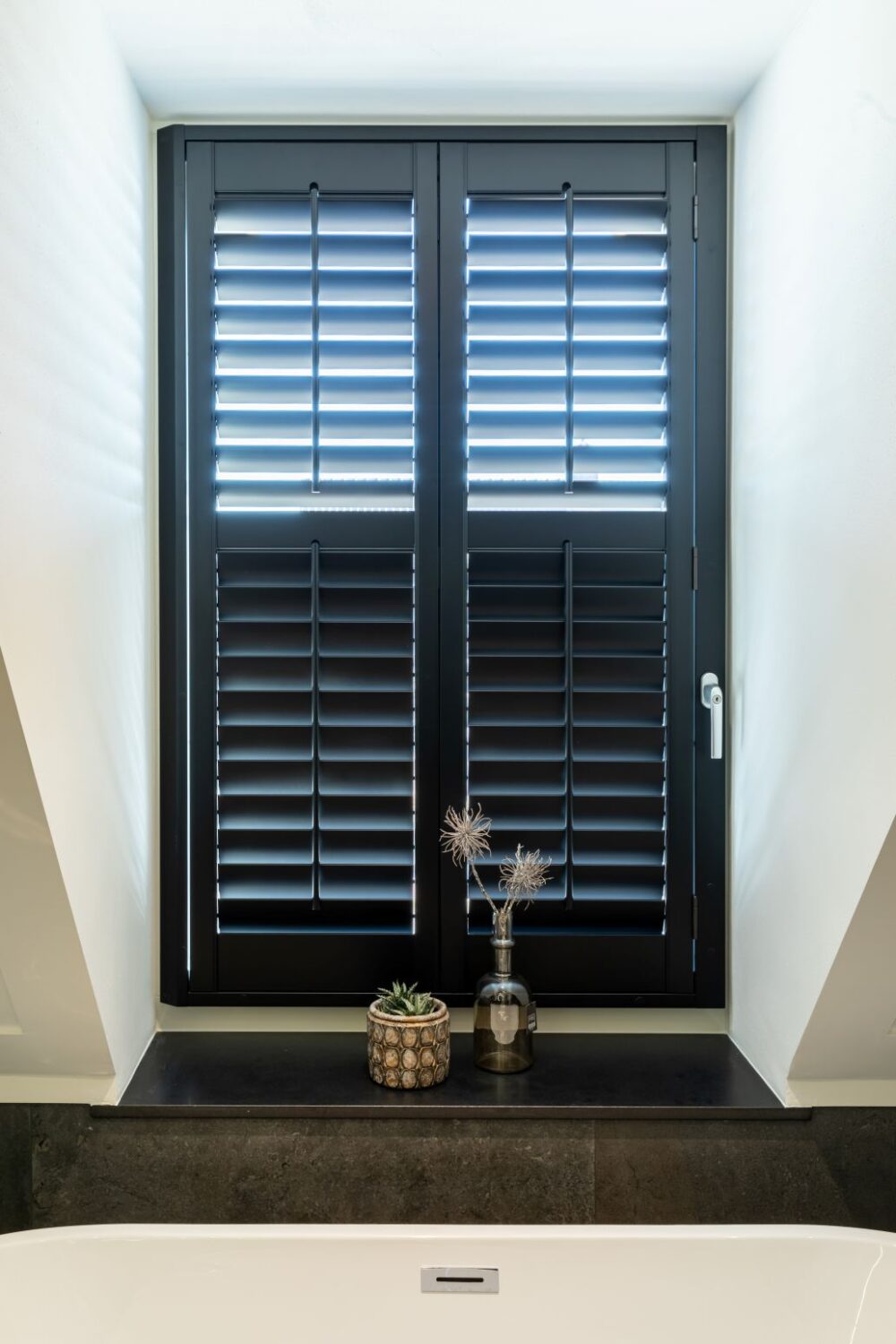 Zwarte shutters in dakkapel op badkamer lamellen half open half dicht.