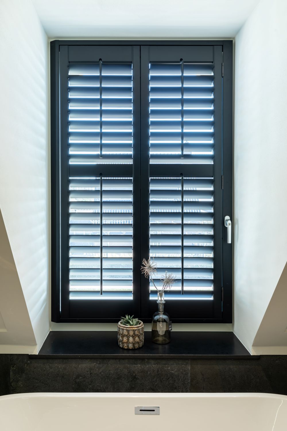 Zwarte shutters in dakkapel op badkamer gekantelde lamellen.