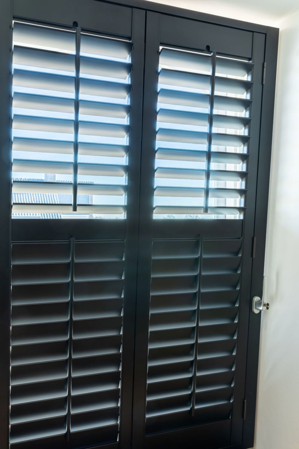 Zwarte shutters op kiepraam lamellen half open half dicht